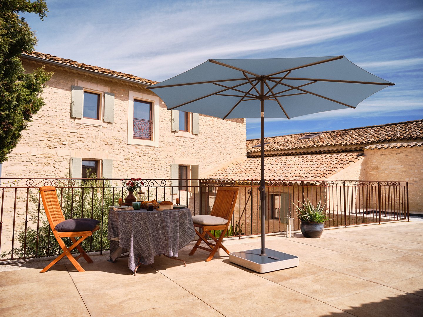 eine mediterrane Terrasse mit einem gemütlichen Sitzplatz geschützt durch einen Sonnenschirm