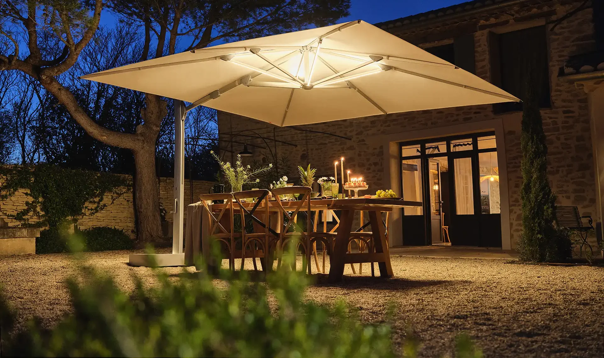 Eine Terrasse im dunklen, beleuchtet und geschützt durch einen Seitenarmschirm